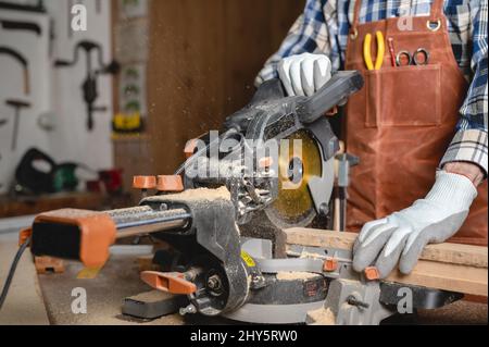 Carpenter using an electric circular saw, cutting piece of wood. High quality photo. Stock Photo