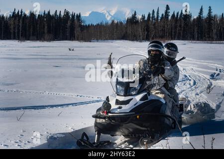 Members of 3rd Battalion, Royal 22e Régiment Canadian Army use snowmobiles to conduct a reconnaissance mission in the training area of Fort Greely AK, with members of the United States Special Forces during Exercise Joint Pacific Multinational Readiness Center 22-02 on March 12, 2022. JPMRC 22-02 is the first Home Station Combat Training Center (HS-CTC) rotation in Alaska. It focuses on Large Scale Combat Operations (LSCO) and is a Cold Weather training event that includes Situational Training Exercise (STX) and a Live Fire Exercise (LFX) in 2QFY22. This exercise will validate the 1/25th Stryk Stock Photo