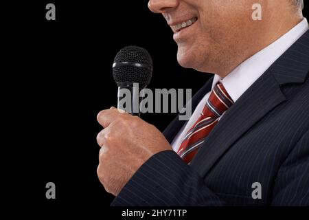 He has the gift of the gab. Cropped image of a mature man in a suit speaking into a microphone. Stock Photo