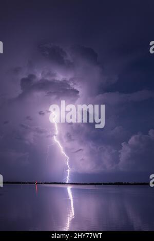 A vertical shot of a striking lightning in the stormy night sky over ...