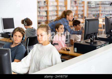 Pupils using computers at lesson, teacher teaching them in class room Stock Photo