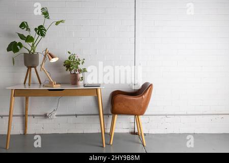 A home office work space set up in a home with concrete floor and brick walls. Scandinavian styled. Stock Photo
