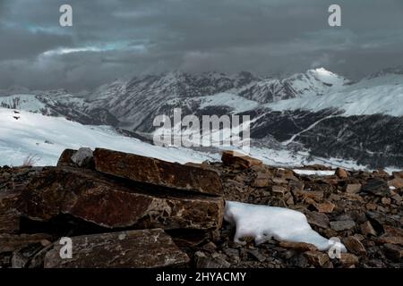 View from the rocky peak to the snow-capped peaks of the mountains Stock Photo