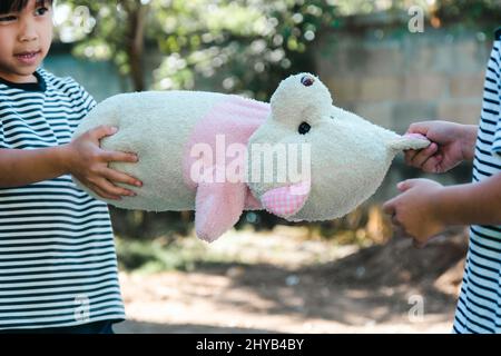 Two sisters in a dispute over a toy at home. Sibling girls snatching doll while stay at home. Relationships difficulties in family concept Stock Photo
