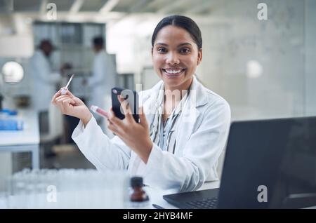 Our cruelty free cosmetics keep you looking good minus the guilt. Shot of a young scientist applying makeup using a smartphone while conducting Stock Photo
