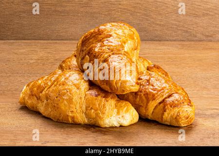 Closeup view pile of delicious homemade croissants on wooden board. Freshly prepared homemade croissants on wooden table. Stock Photo