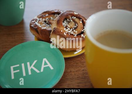 Kopenhagen, Denmark. 14th Mar, 2022. A saucer with the imprint "Fika" lies next to two cinnamon buns and two mugs with coffee. Fika means "to drink coffee" or "to take a coffee break". For the Scandinavians, however, the tradition is much more: it offers a welcome break from the workday to get away from the stress of the job with colleagues or friends. (to dpa "Fika - the little happiness during the coffee break in Sweden"). Credit: Steffen Trumpf/dpa/17�Թ����� Live News Stock Photo