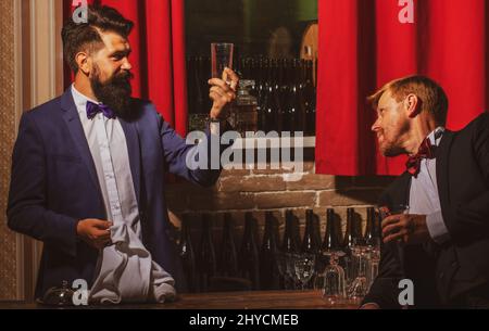 Barmen and customer. Alcohol beverage. Barman at counter. Hipster in bar. Old traditional whiskey drink. Gentlemans beverage. Stock Photo