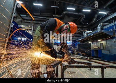 man work in home workshop garage with angle grinder, goggles and construction gloves, sanding metal makes sparks closeup, diy and craft concept Stock Photo