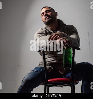Alcoholic man with bottles wine cry. Depressed crying man. Hangover depressed man after hard drinking. Bad alcohol habits. Alcohol abuse. Stock Photo