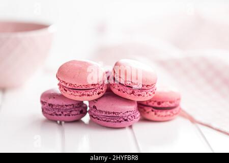 Sweet pink macarons. Traditional french macaroons. Tasty dessert on a white table. Stock Photo