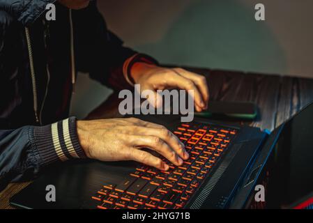 Hands in type on a laptop keyboard in close-up. The concept of cybercrime fraud and identity theft. Stock Photo