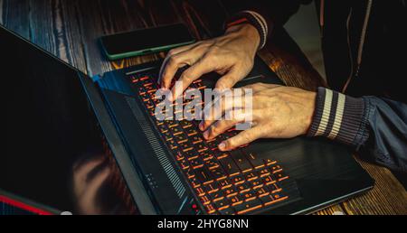 Hands in type on a laptop keyboard in close-up. The concept of cybercrime fraud and identity theft. Stock Photo