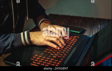 Hands in type on a laptop keyboard in close-up. The concept of cybercrime fraud and identity theft. Stock Photo