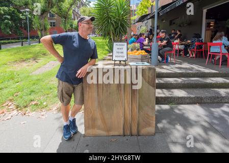 A middle-aged white male man (model rel'd) stands smiling, waiting to be seated at a cafe in the Sydney suburb of Ultimo, New South Wales, Australia Stock Photo