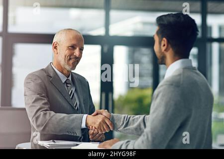 Glad to have you on board. Cropped shot of two businessmen shaking hands in an office. Stock Photo