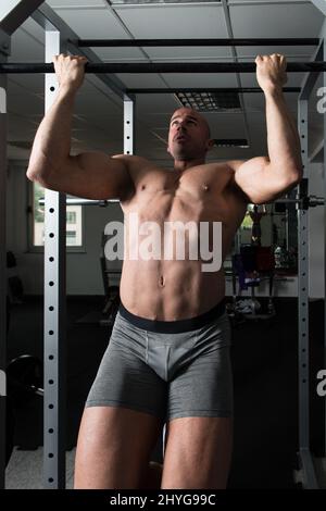 Man Athlete Doing Pull Ups - Chin-Ups In The Gym Stock Photo