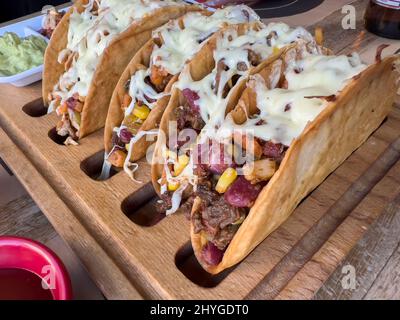 Chicken and cheddar cheese tacos on a taco board with sauces on the side Stock Photo