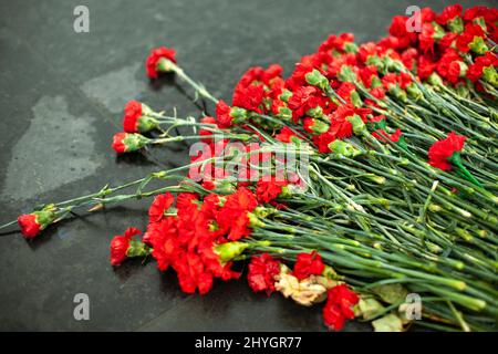 Flowers on memorial. Details of funeral decoration. Bouquet of flowers on grave. Mourning ceremony. Stock Photo