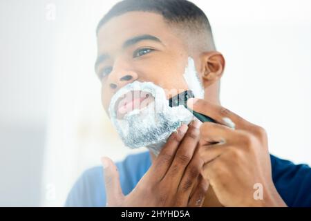 Woke up in the mood to shave this morning. Shot of young man focusing as he shaves his face. Stock Photo