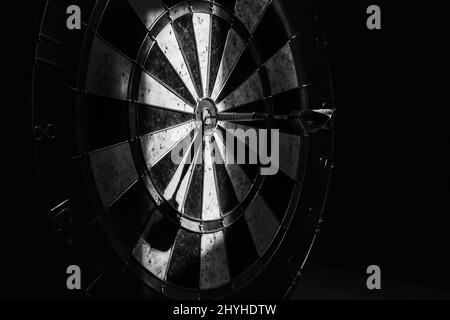 Closeup of a darts board with a dart hits the target, shot in grayscale - concept of success Stock Photo