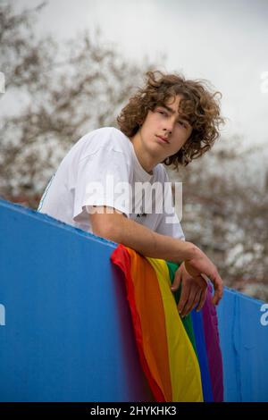 young gay guy with curly hair with gay pride flag Stock Photo