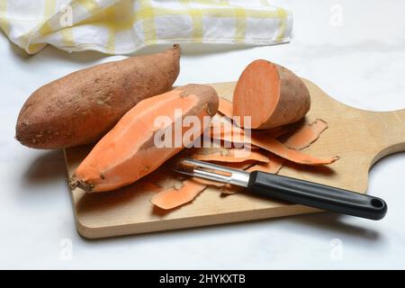 Sweet potato (Ipomoea batatas), peeled sweet potato with potato peeler Stock Photo