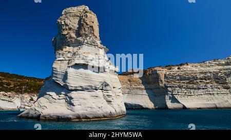 Volcanic rocks in the sea, sailboat, lava coast, blue cloudless sky, near Kleftiko beach, Milos island, Cyclades, Greece Stock Photo