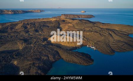 Drone shot, morning atmosphere, caldera, view of volcanic islands Nea Kameni with small harbour and boats, Palea Kameni and Aspronisi, view of Stock Photo