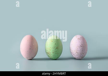Three decorative pastel eggs on blue background. Happy Easter greeting card with copy space. Stock Photo