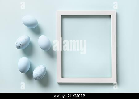 Easter frame with blue eggs on blue background. Spring monochrome greeting card with copy space. Top view. Stock Photo
