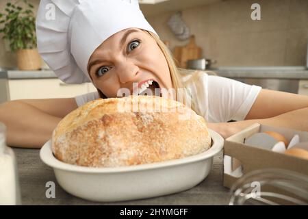 Young attractive chef woman wants to eat bread Stock Photo