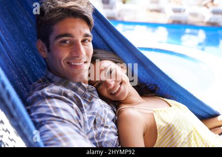 Wrapped up in him. Portrait of an affectionate young couple lying in a hammock. Stock Photo