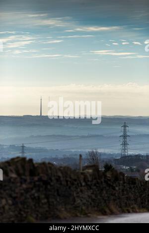 West Yorkshire, UK. 15th Jan, 2022. UK Weather.Shelf, West Yorkshire, UK. 15th March 2022.  Light mist in the valley viewed from Pepper Hill, Shelf, West Yorkshire, UK with the Grade 2 listed transmitter of Emley Moor on the skyline. Credit: Windmill Images/Alamy Live News Stock Photo