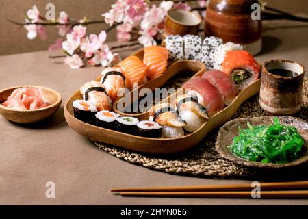 Sushi rolls set. Traditional japanese dish sushi rolls with fresh salmon, tuna, eel, prawns on rice. Serving on wooden plate with soy sauce, wakame sa Stock Photo