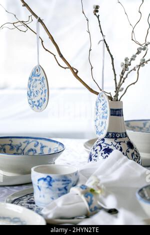 Elegant Easter table setting with empty painted porcelain tableware, plates and bowls, Easter eggs decorations, branches in vase on white tablecloth i Stock Photo