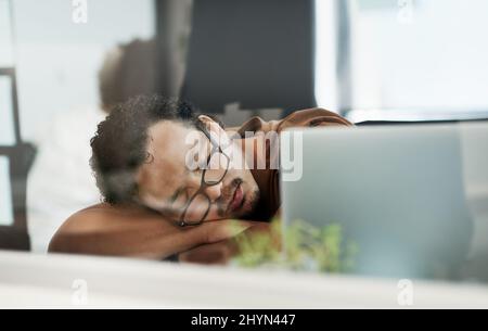 I think Ill just take a nap right here. Shot of a handsome young businessman lying on his desk and sleeping in the office. Stock Photo