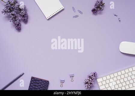 The workspace of a blogger or freelancer Flat lay with a keyboard, notebooks and lilac branches, stationery on a lilac background with a copy space Stock Photo