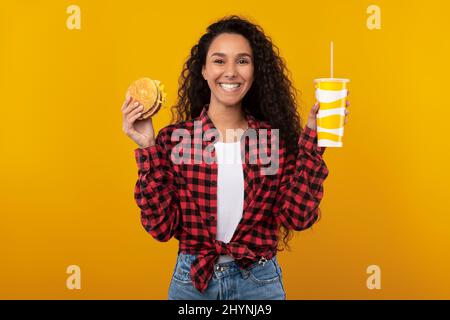 Funny Young Lady Holding Burger And Drink Stock Photo