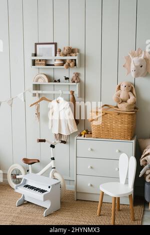 Cozy interior of a children's room, a play area. Toys, a bicycle, a piano, a chest of drawers and clothes on a hanger. Scandinavian apartment style Stock Photo