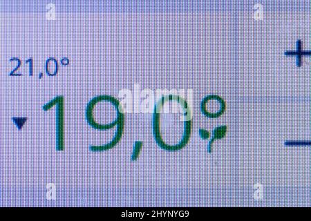 Digital display of a thermostat at home. Turning down temperature to save energy. Gas saving. Stock Photo