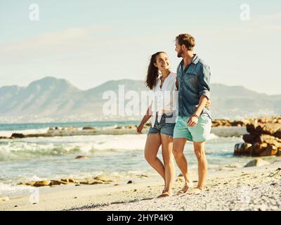 We share a deep love for the beach. Shot of a young married couple walking on the beach. Stock Photo