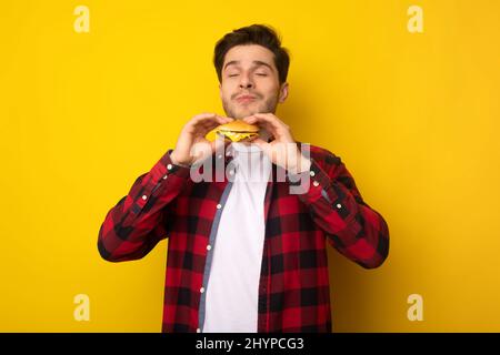 Closeup Of Excited Guy Eating Tasty Burger At Studio Stock Photo