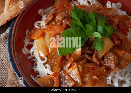 Hot Uighur dish served with herbs and flatbread. Stock Photo