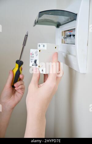 A woman changes an automatic fuse EKF in a home electrical panel. Self repair and replacement of electricity equipment in the apartment, diy - Moscow, Stock Photo