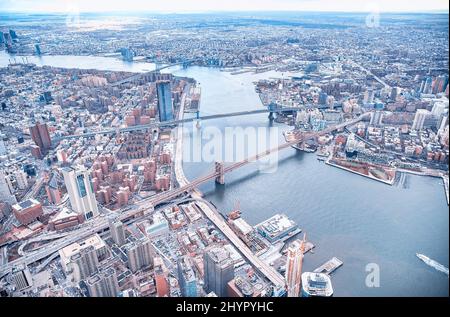 New York City from helicopter point of view. Brooklyn, Manhattan and  Williamsburg Bridges with Manhattan skyscrapers on a cloudy day. Stock Photo