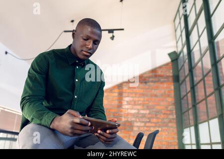 African american young businessman using digital tablet while sitting in modern office Stock Photo