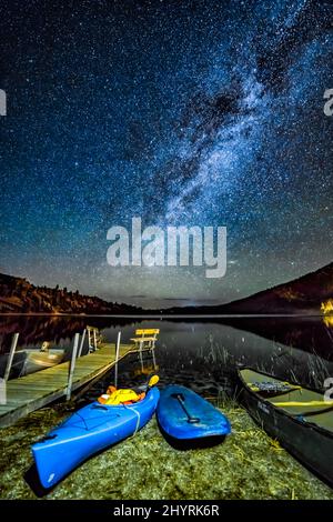 Photo of pier with boats around the water under night sky full of stars Stock Photo