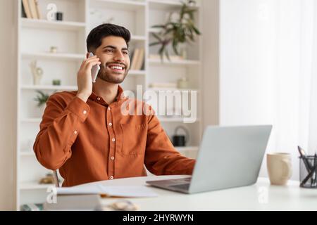 Smiling bearded man working and talking on phone at home Stock Photo