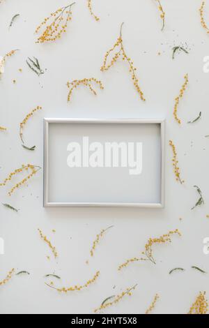 mockup with yellow mimosa flowers and blank photo frame with copy space. Spring, Easter concept Stock Photo